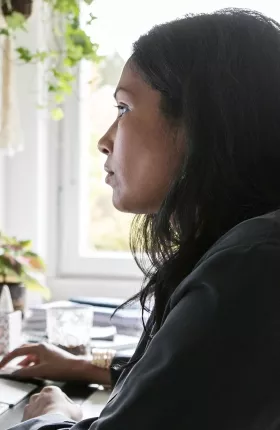 Woman with brown hair browsing on a desktop computer in home office