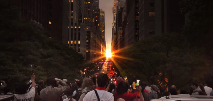 A crowd of people staring at the sunset between two city buildings