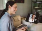 Woman smiling at a piece of paper while video conferencing with another woman