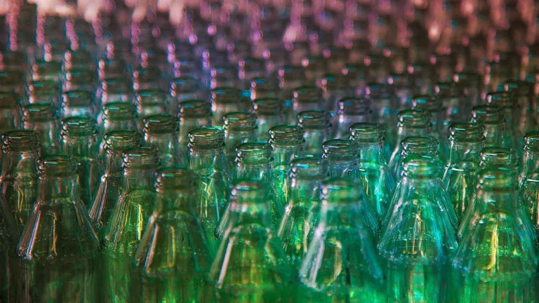 The tops of glass bottles organized in a gradient from green to purple