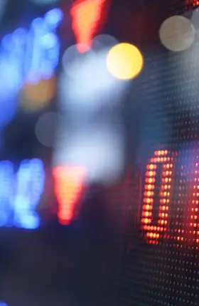 Close-up, blurred shot of blue, red, and yellow-lit numbers on a digital screen
