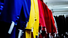 The arm sleeves of blue, yellow, and red shirts hanging up