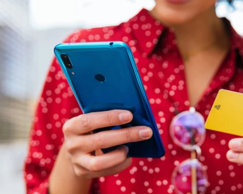 Person in a red shirt holding a blue cellphone and yellow card