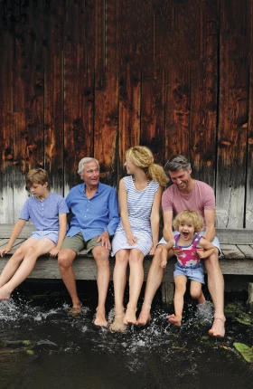 Family sitting together on jetty splashing with water