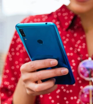 Person in a red shirt holding a blue cellphone and yellow card