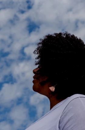 Side profile of a Black woman standing against a blue sky