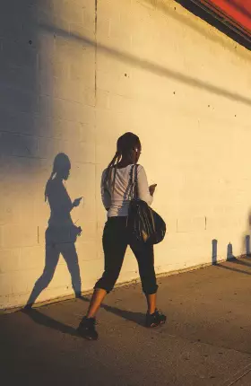 Woman with a Bag Over Her Shoulder Walking on sidewalk