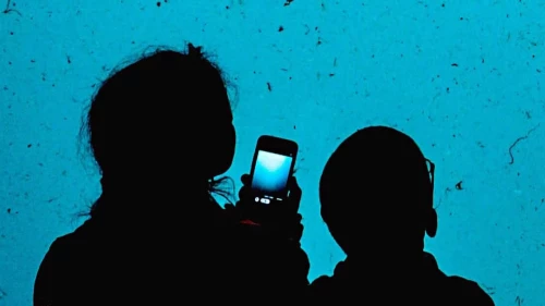 Woman and child with smartphone in hand looking at aquarium