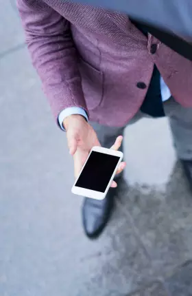 Person holding umbrella and looking down at cell phone