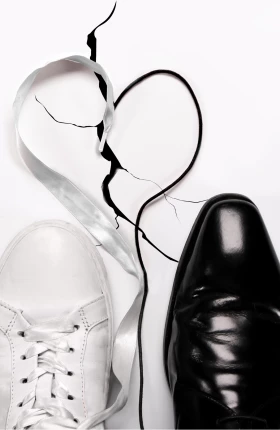 Above view of a men's left white sneaker and right black dress shoe