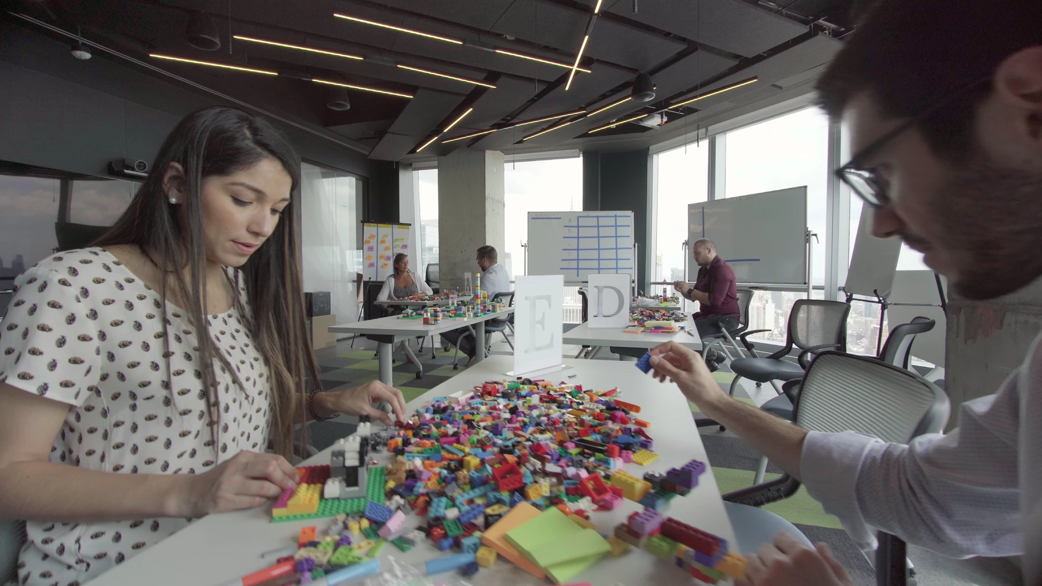 Women and Men Sitting on a Table Building with Colorful Legos