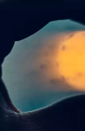 Close-up of person's hand holding sun between fingertips