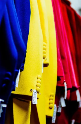 The arm sleeves of blue, yellow, and red shirts hanging up