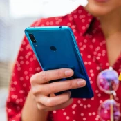 Person in a red shirt holding a blue cellphone and yellow card