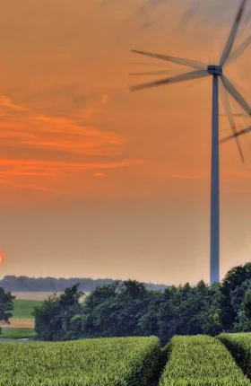Energy windmills on a farm with a sunset