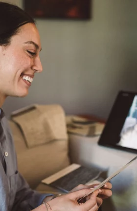 Woman smiling at a piece of paper while video conferencing with another woman