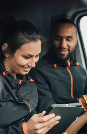 Man and woman inside a van smiling at a tablet