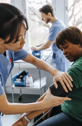 Female healthcare worker checking senior patient's blood pressure in medical examination room