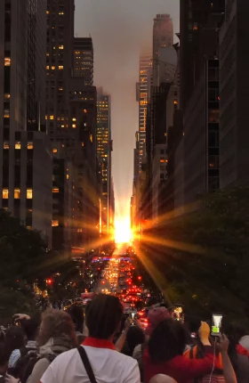 A crowd of people staring at the sunset between two city buildings