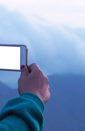 Hands holding a smartphone taking a photo of the clouds