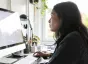 Woman with brown hair browsing on a desktop computer in home office