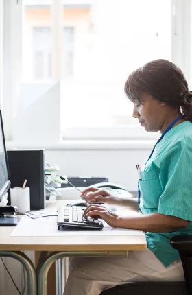 Nurse sitting at desk typing on keyboard