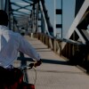 Person riding a bike over a metal covered bridge