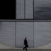Side view of man with briefcase walking in front of concrete building