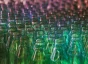 The tops of glass bottles organized in a gradient from green to purple