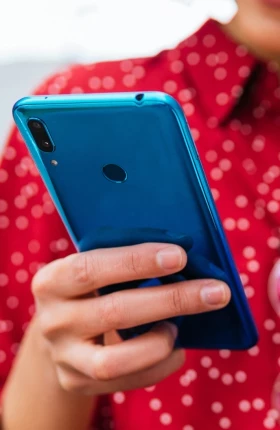 Person in a red shirt holding a blue cellphone and yellow card