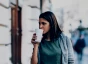 Woman in sweater walking outside and drinking coffee