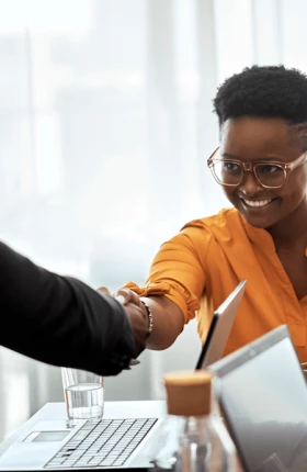 Smiling businesswoman shaking hand with male coworker at office