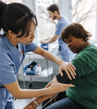Female healthcare worker checking senior patient's blood pressure in medical examination room