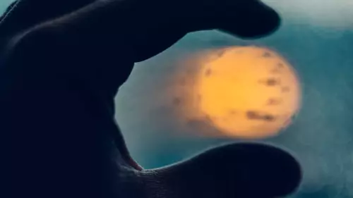 Close-up of person's hand holding sun between fingertips