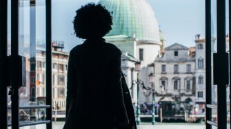 Silhouette of a Woman Walking Through Double Doors to go Outside