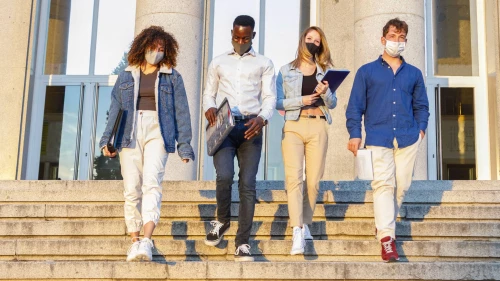 4 students wearing face masks walking down the stairs