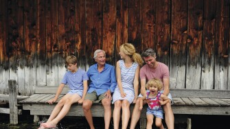 Family sitting together on jetty splashing with water