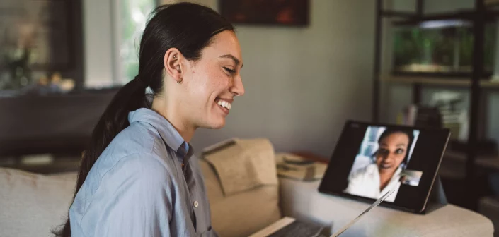 Woman smiling at a piece of paper while video conferencing with another woman