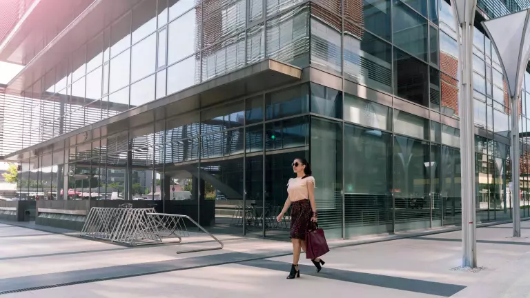 Woman walking in front of a glass building