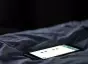 Close-up of a smartphone laying on sheets