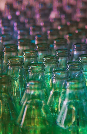 The tops of glass bottles organized in a gradient from green to purple