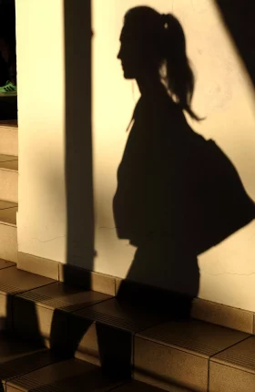 Shadow of a person with a ponytail carrying a handbag