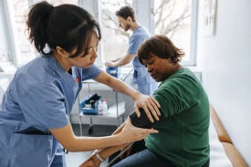 Female healthcare worker checking senior patient's blood pressure in medical examination room