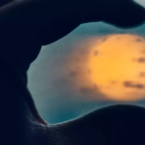 Close-up of person's hand holding sun between fingertips
