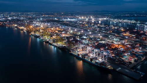 HIGH ANGLE VIEW OF ILLUMINATED CITY AT WATERFRONT