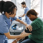 Female healthcare worker checking senior patient's blood pressure in medical examination room