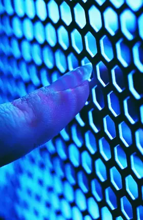 Close-up of person's finger touching blue-illuminated metal mesh
