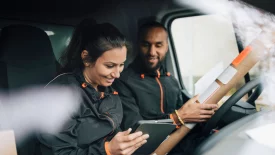 Man and woman inside a van smiling at a tablet