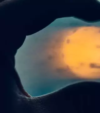 Close-up of person's hand holding sun between fingertips